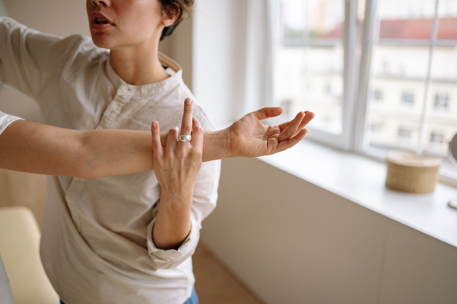 A physical therapist supporting a patient's arm through a shoulder range-of-motion stretch in a treatment room