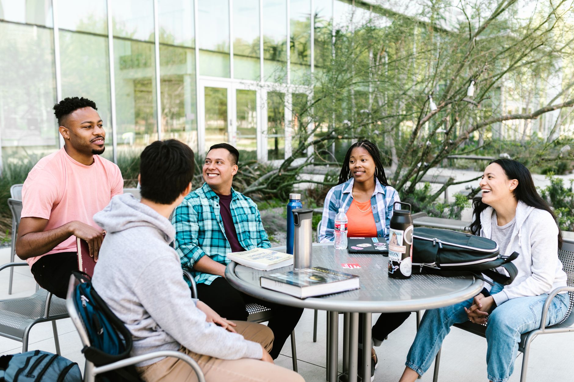 Four students working through notes together at an outdoor table on a college campus