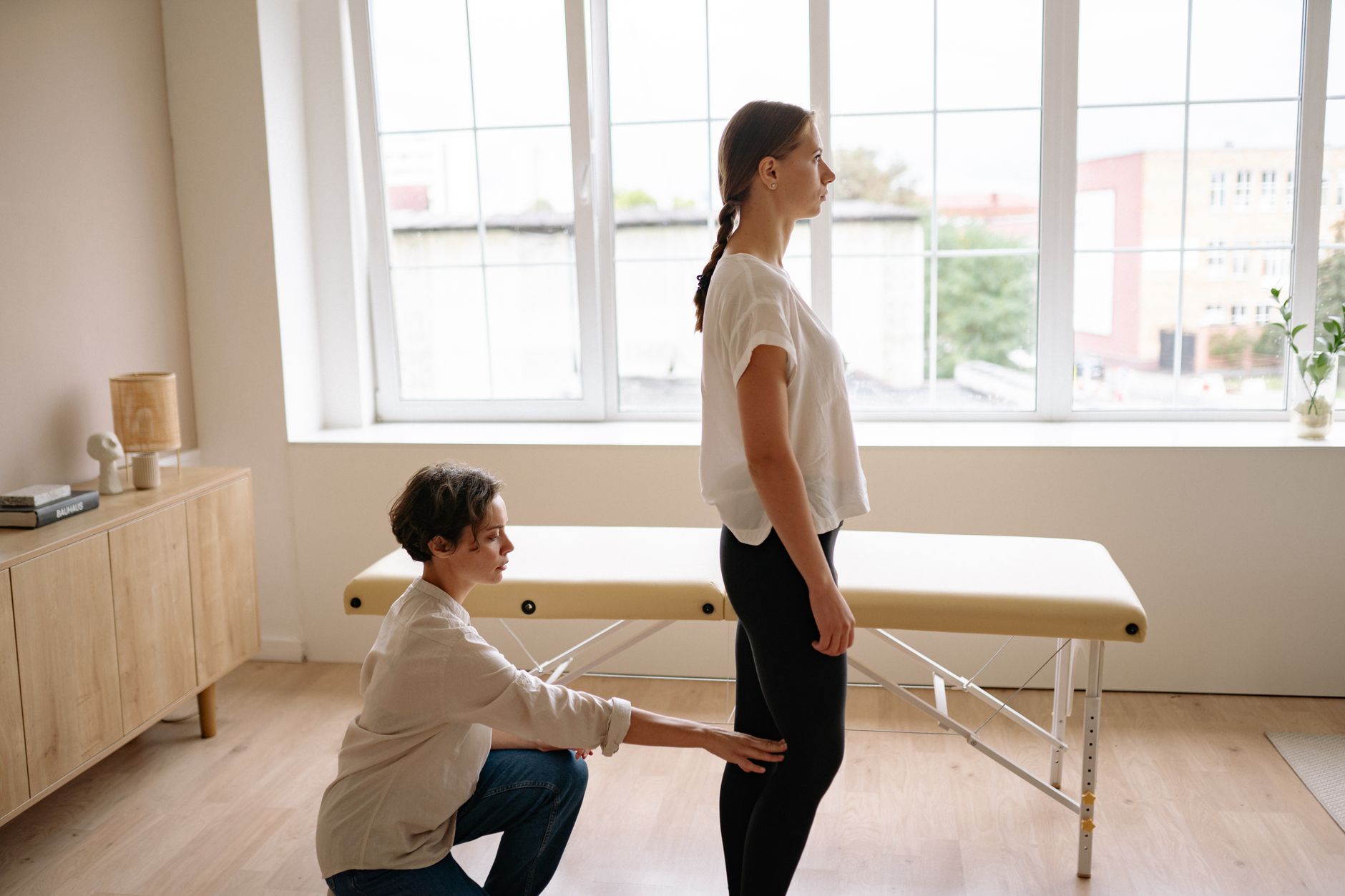 A clinician assessing the back of a standing client's knees during a posture check