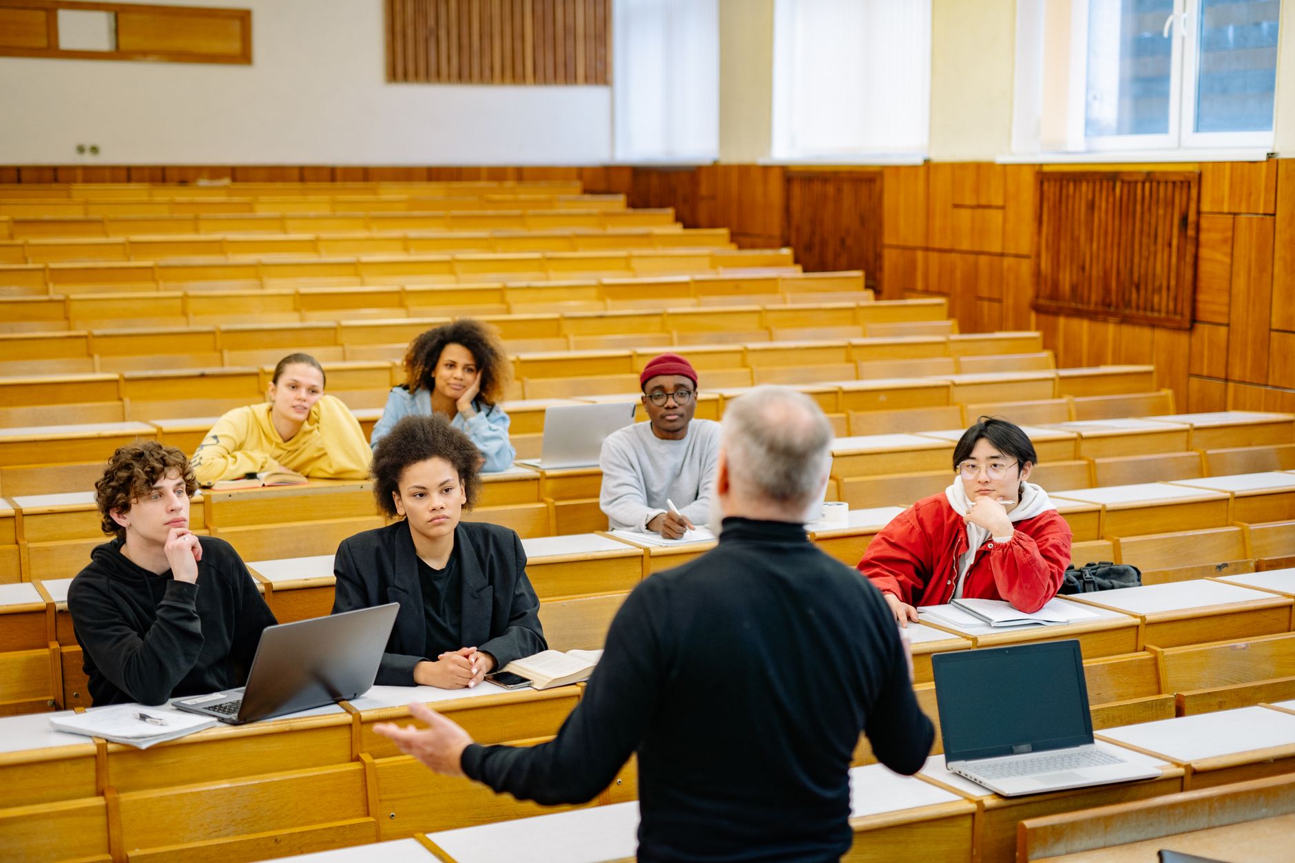 A lecturer addressing a full university lecture hall of seated students