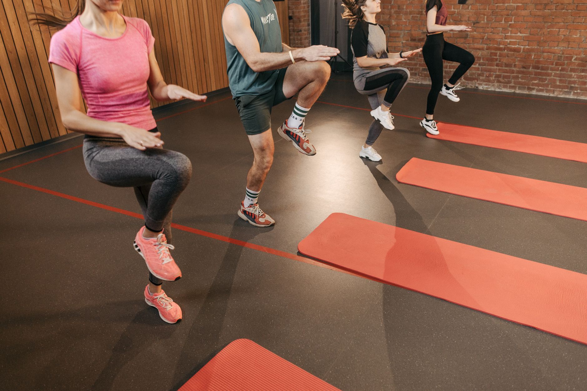 A group of adults driving their knees up in unison during an indoor exercise class