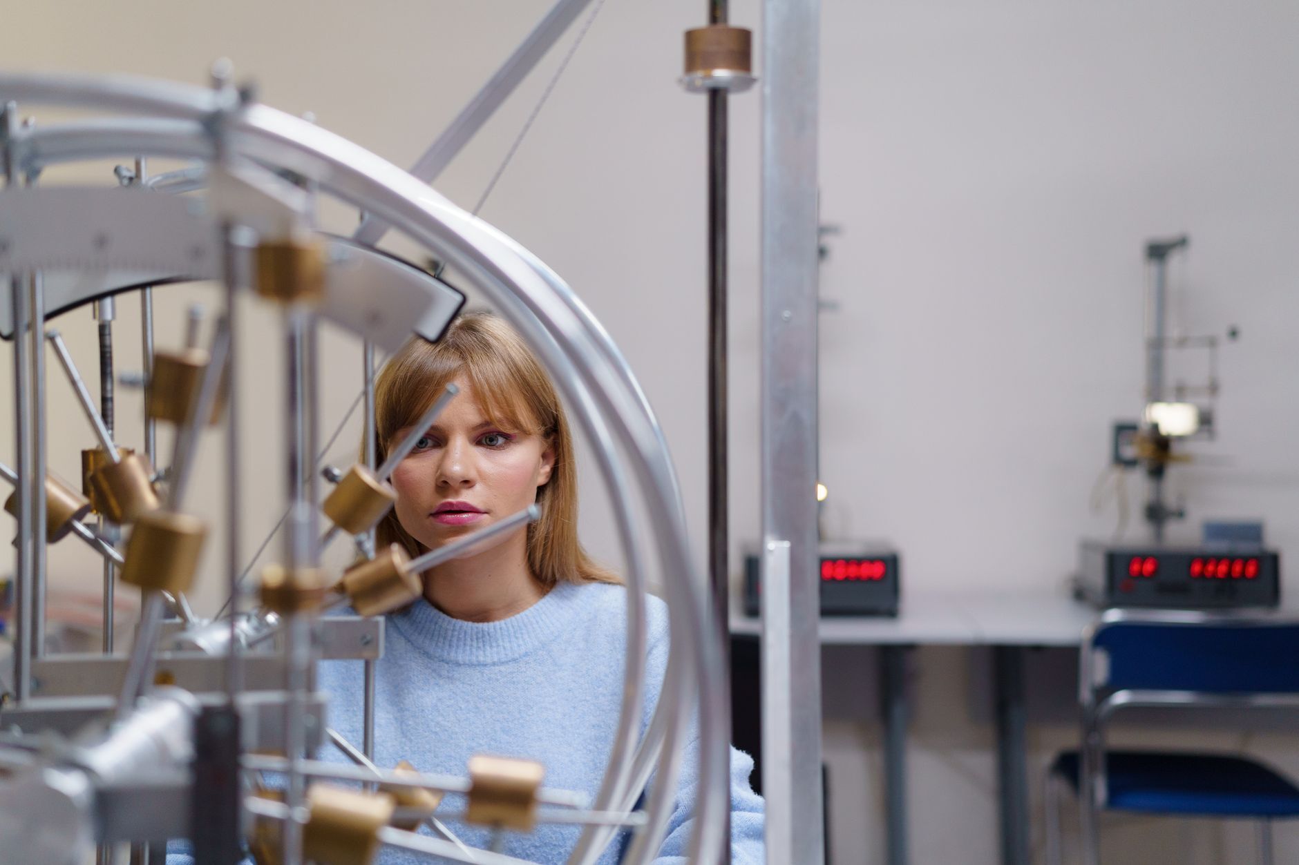 A university student studying a mechanics apparatus in a science teaching laboratory